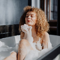Woman in bath using Mumu Bath Signature Hydrating Facial Soap